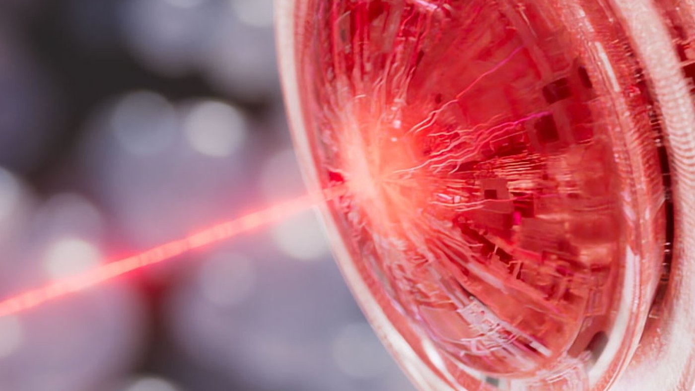 A macro 3D render of a red laser beam hitting a glossy red dome with circuit patterns inside, against a blurred background
