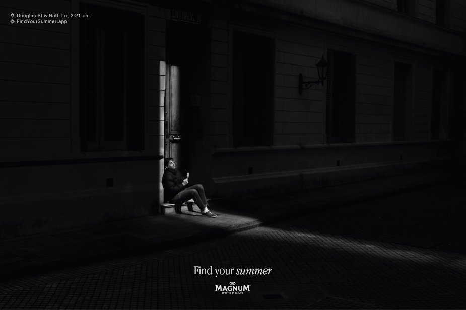 A black and white Magnum poster of a man sitting in a single shaft of sunlight in a dark street, with a street corner and time in the top left and the line Find your summer