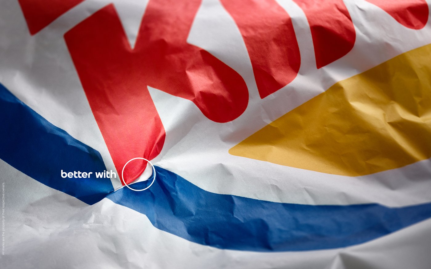 Better With Pepsi print ad showing a crumpled burger wrapper whose folds form the Pepsi globe inside a thin white circle